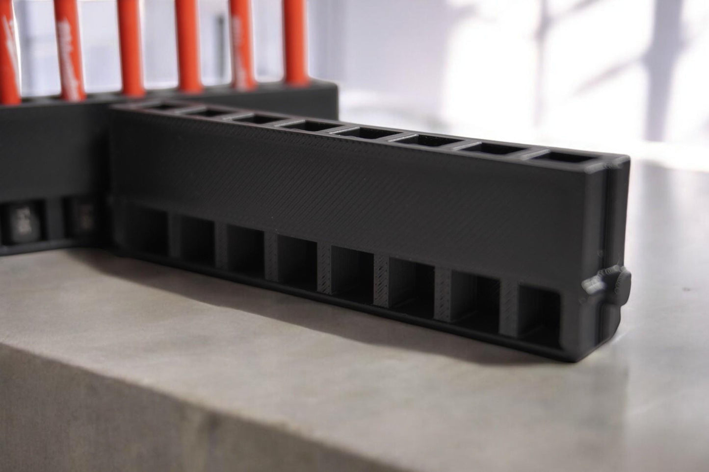 long bit holder with a black design, featuring a secure cover and slots for multiple drill bits.