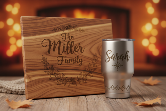 Laser engraved cutting board and tumbler with personalized names and decorative design on a wooden tabletop.