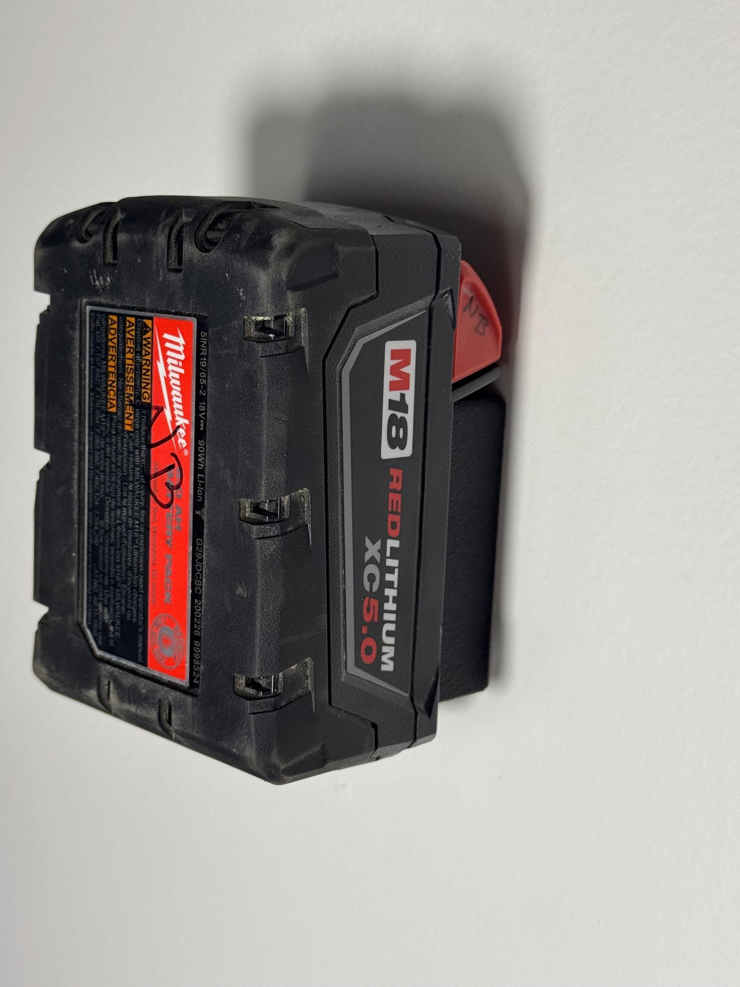 Milwaukee M18 battery clipped securely into wall holder