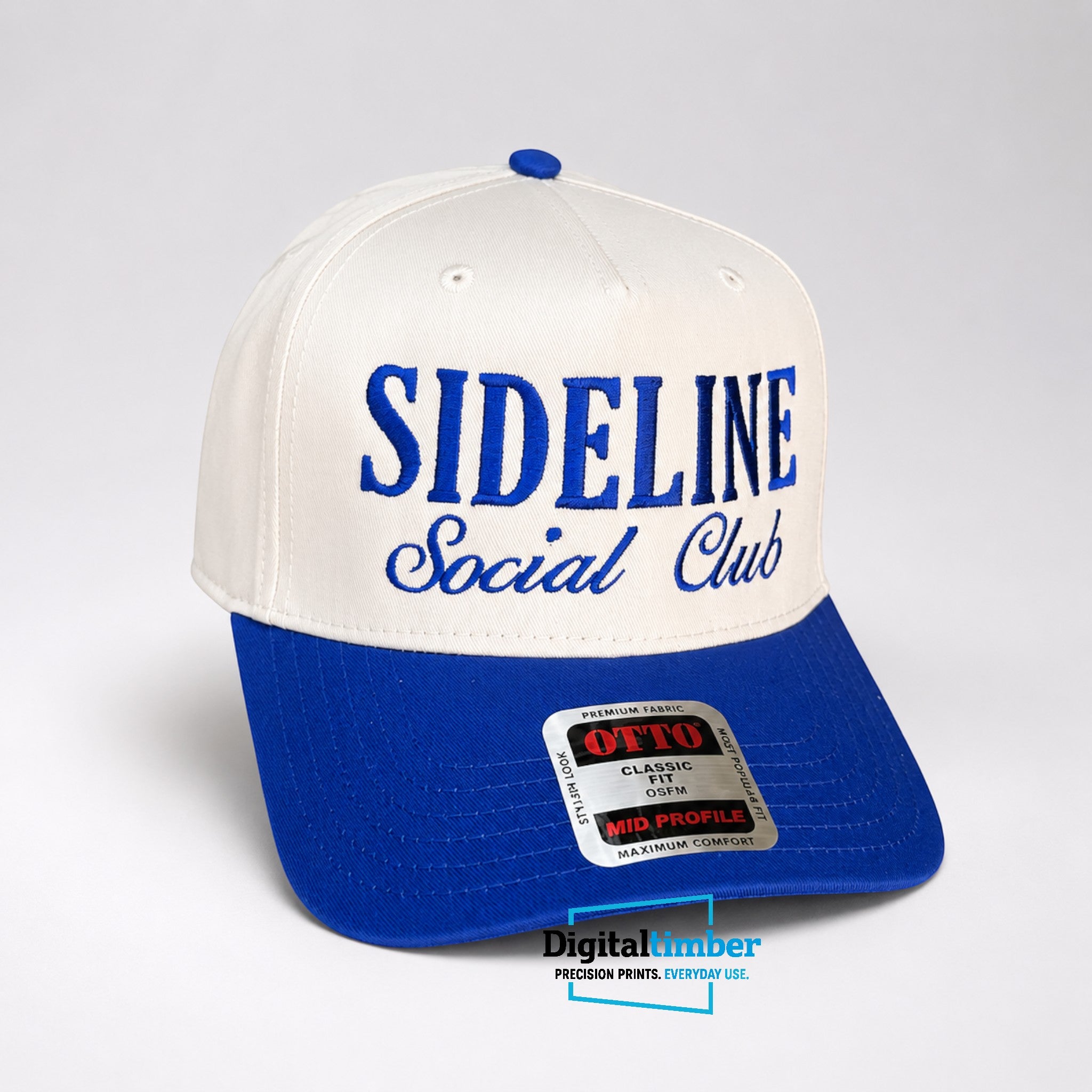 A two-tone baseball cap with an off-white crown and a royal blue brim, featuring 'SIDELINE Social Club' embroidered on the front. A blue button tops the crown, and a silver and red 'OTTO Classic Size Mid Profile' sticker is visible on the brim.