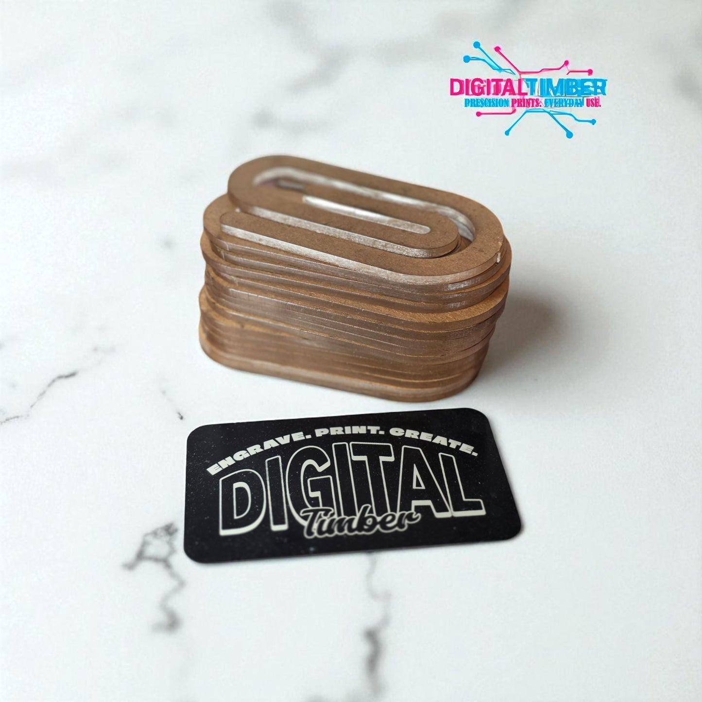 Stack of clear acrylic jumbo paper clip blanks for sublimation on a white marble surface with DigitalTimber branding card