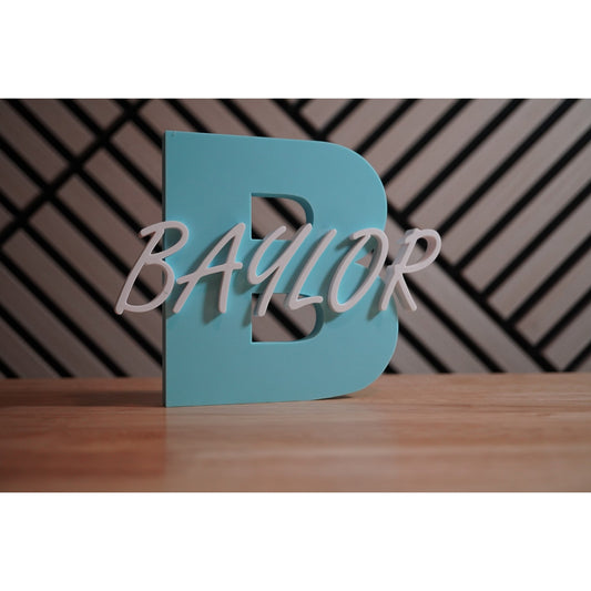 Teal letter 'B' with 'Baylor' in white on a wooden surface and patterned wall background