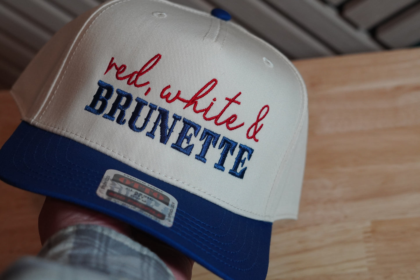 Cap with 'red, white & BRUNETTE' text on a wooden surface