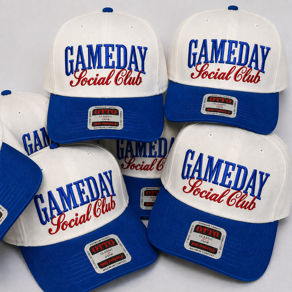 Five white and royal blue baseball caps with 'GAMEDAY Social Club' embroidered on the front, arranged together on a light gray background.