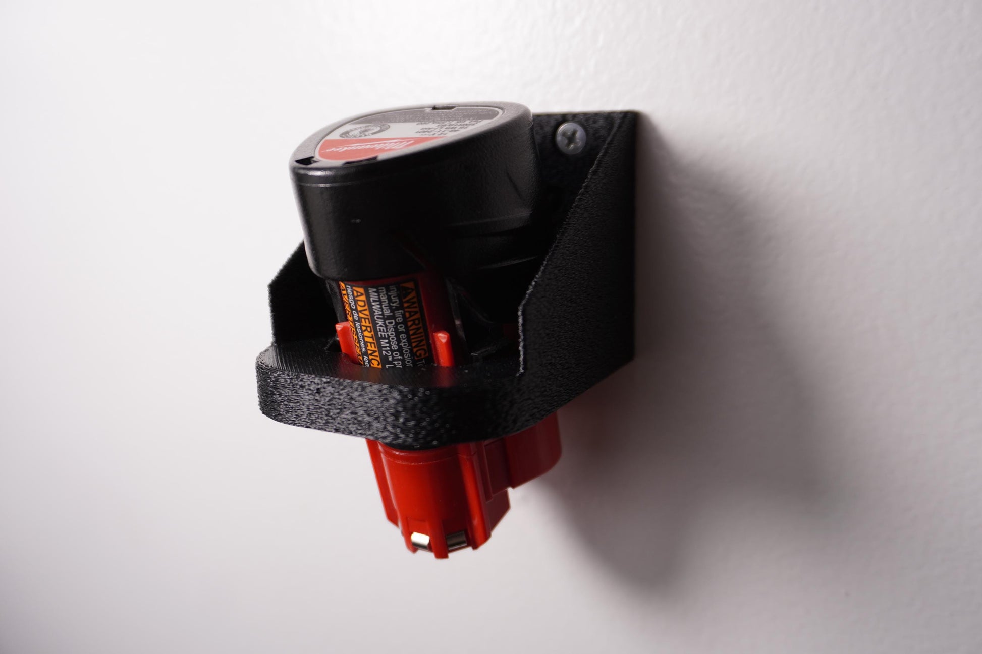 Wall-mounted M12 battery holder made from PETG, featuring multiple slots for securely storing M12 batteries. The holder is mounted on a wall, showcasing its compact and organized design. (etsy image id: 6576133745)