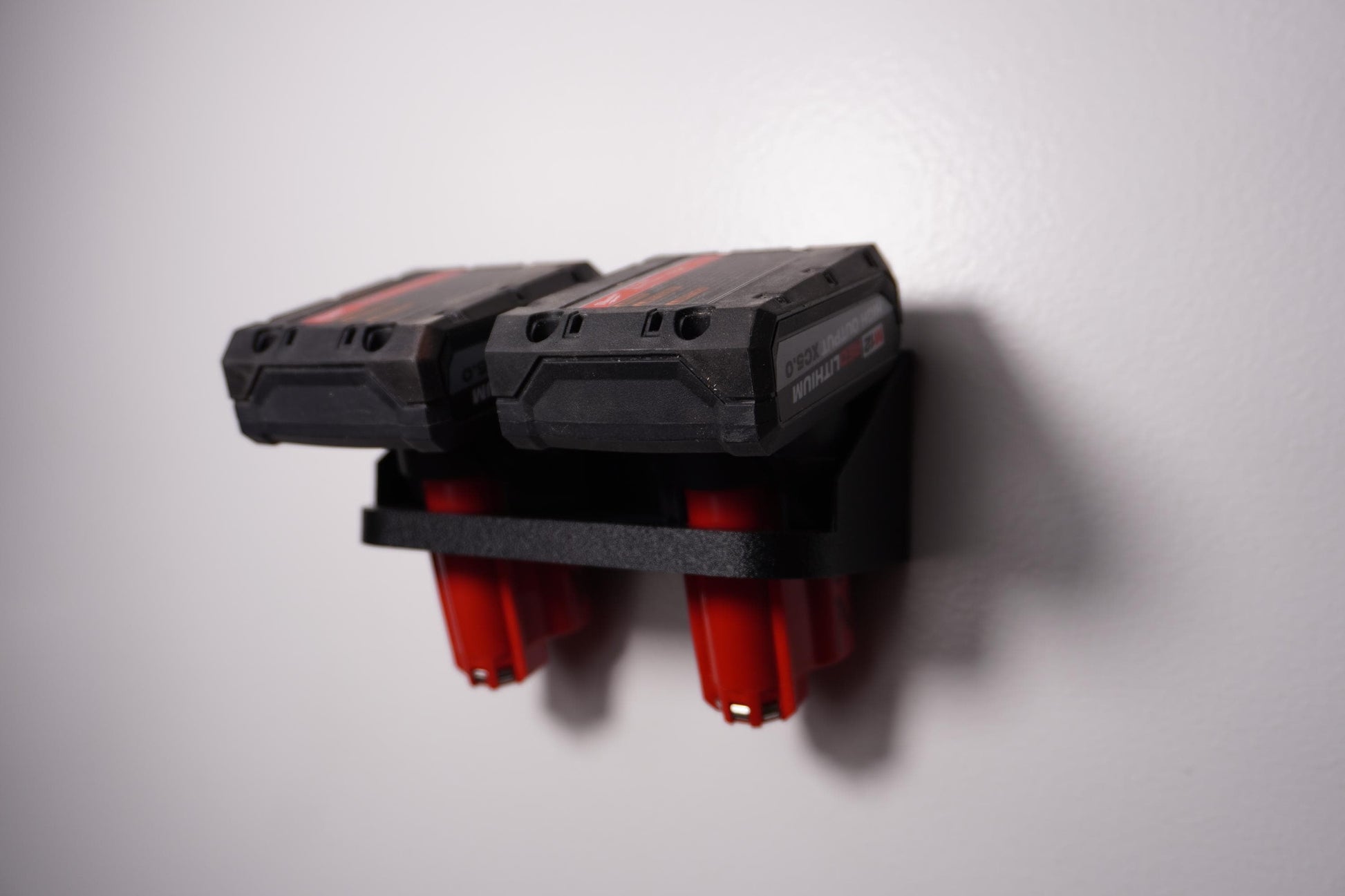 Wall-mounted M12 battery holder made from PETG, featuring multiple slots for securely storing M12 batteries. The holder is mounted on a wall, showcasing its compact and organized design. (etsy image id: 6576133823)