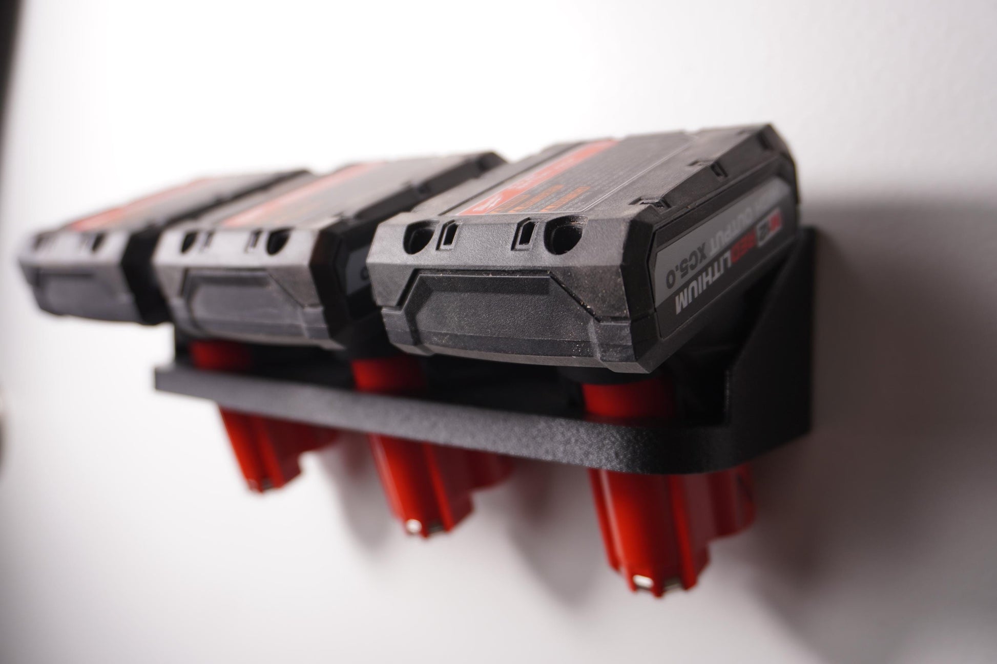 Wall-mounted M12 battery holder made from PETG, featuring multiple slots for securely storing M12 batteries. The holder is mounted on a wall, showcasing its compact and organized design. (etsy image id: 6576133943)