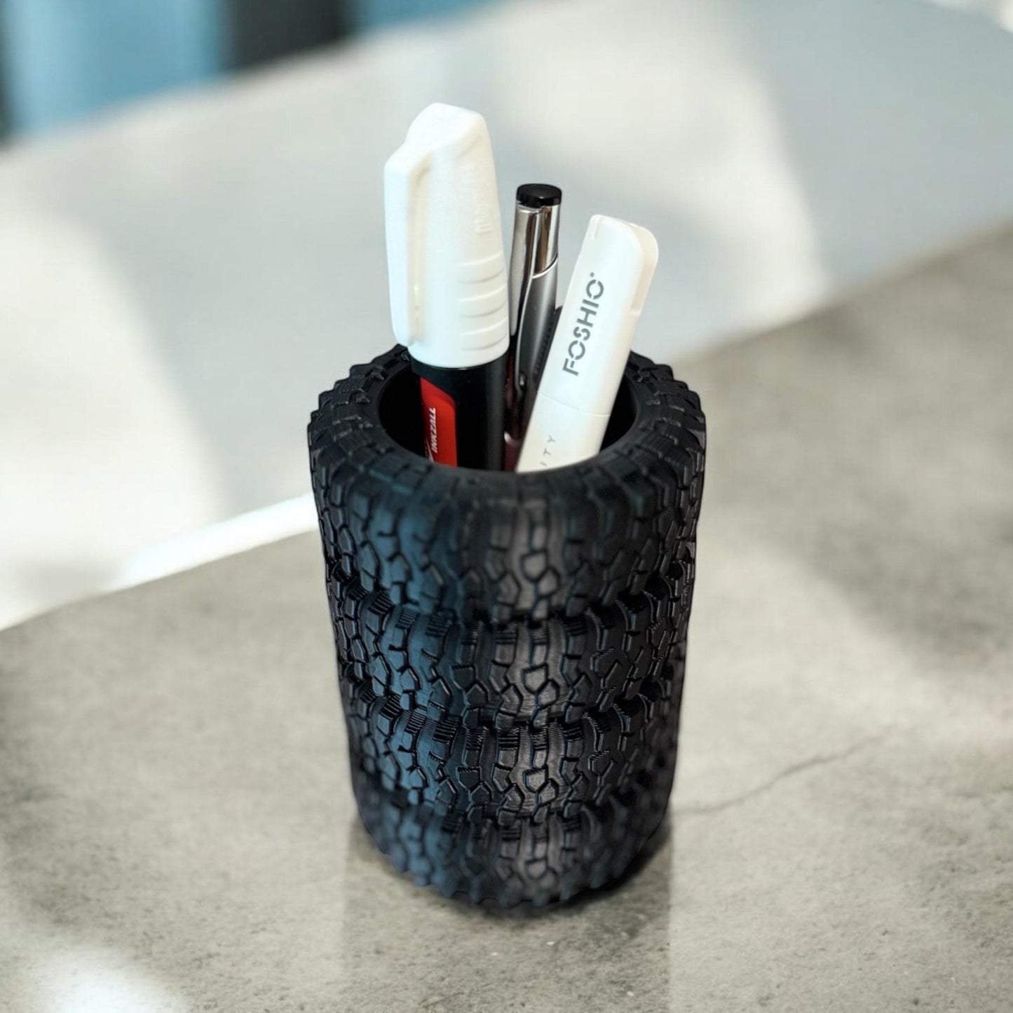 Black stacked tire pen holder standing upright with two white pens inside on a light gray surface.  Made by DigitalTimber. (etsy image id: 6789654413)