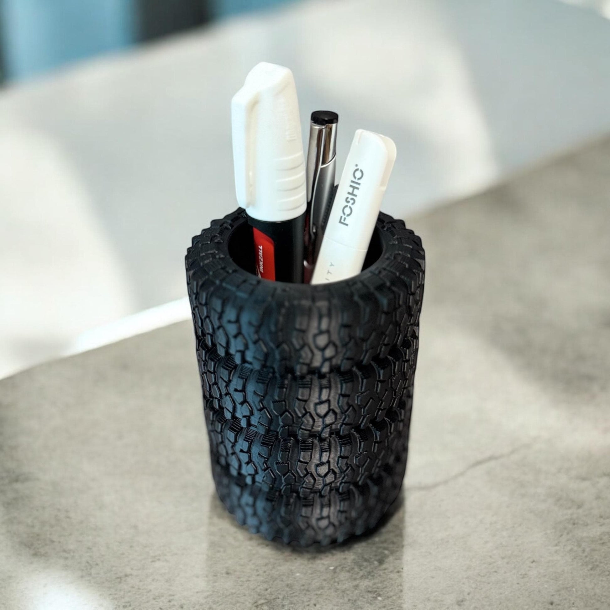 Black stacked tire pen holder standing upright with two white pens inside on a light gray surface.  Made by DigitalTimber. (etsy image id: 6789654413)