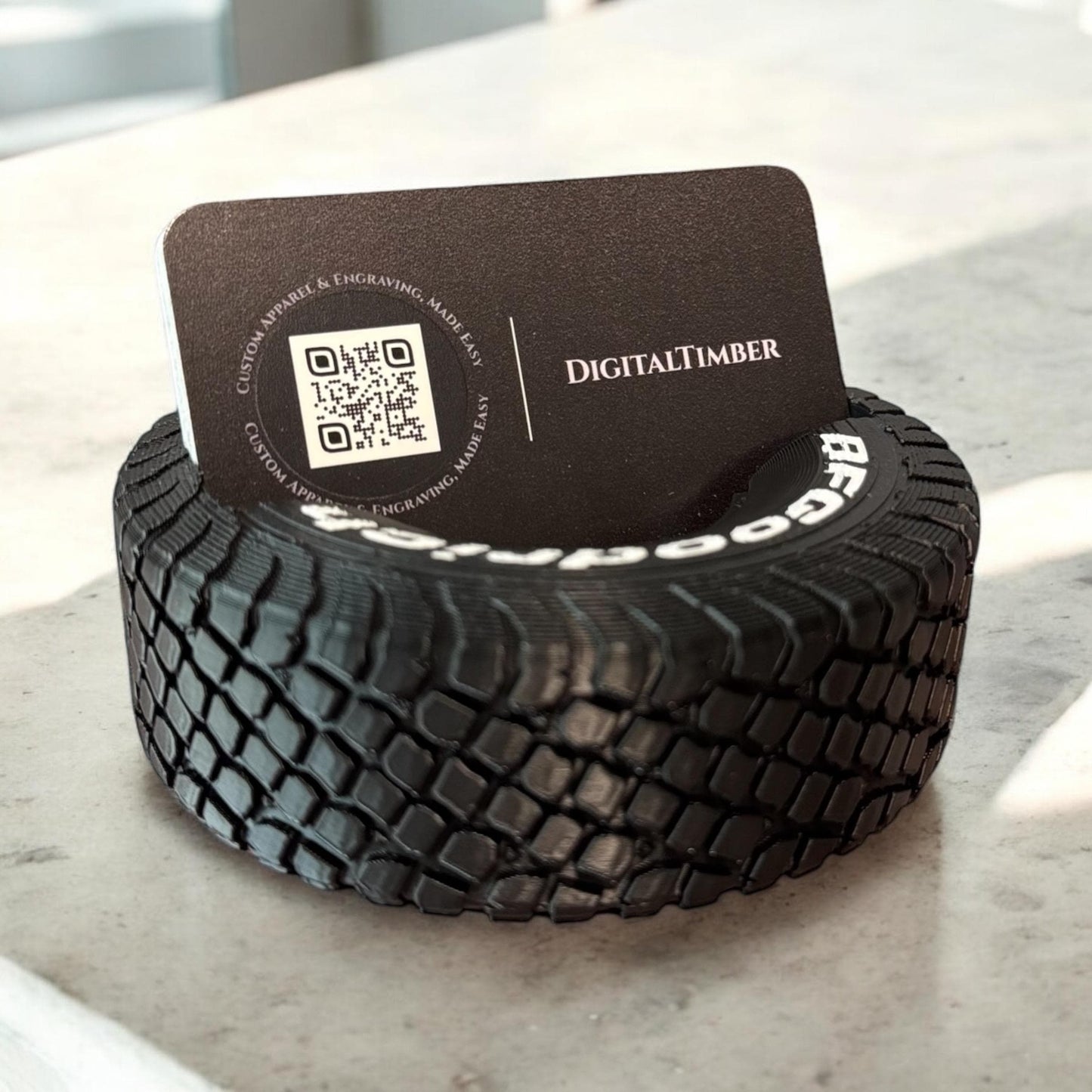 Close-up of round tire business card holder displaying a black card with white logo on a marble background.  Made by DigitalTimber. (etsy image id: 6789656957)