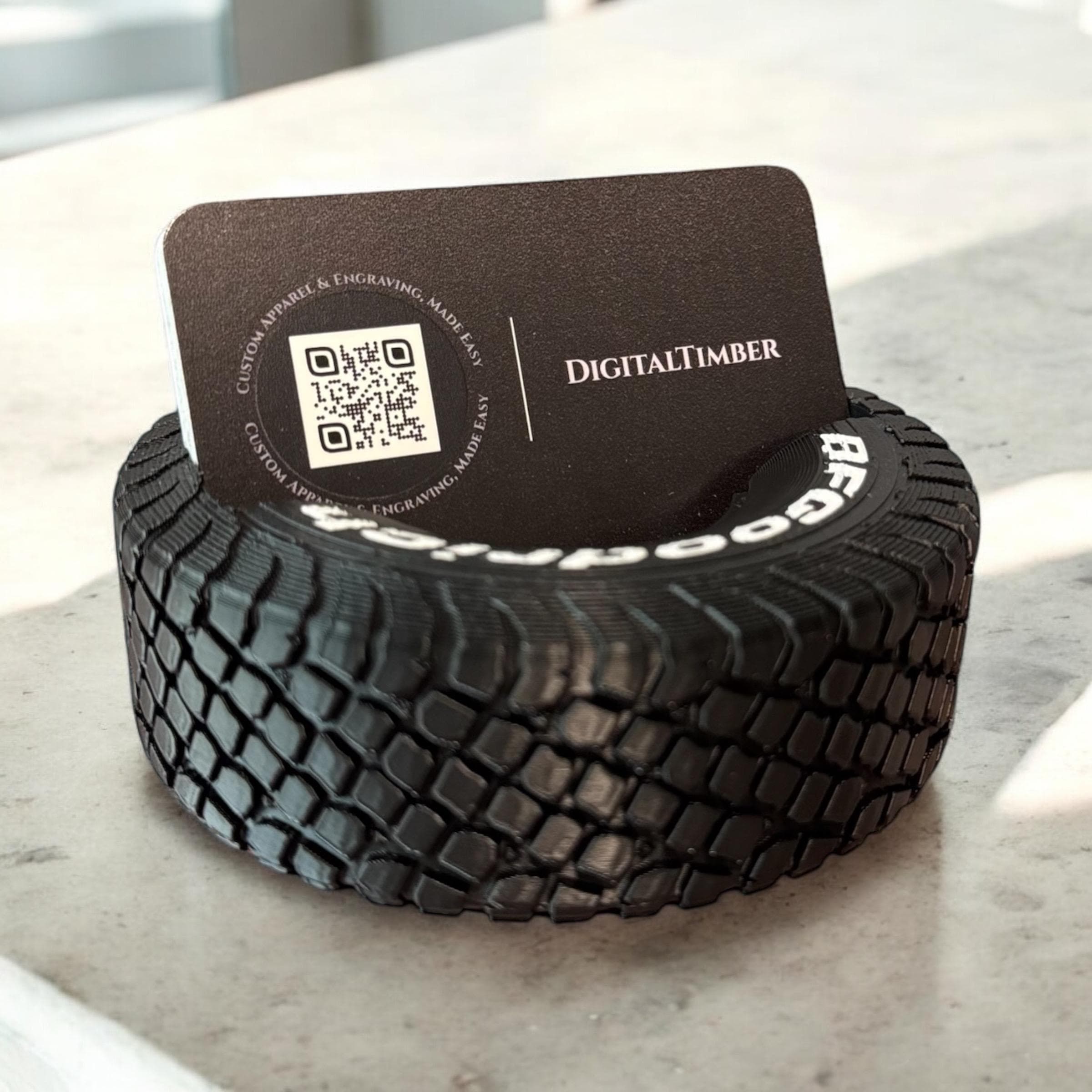 Close-up of round tire business card holder displaying a black card with white logo on a marble background.  Made by DigitalTimber. (etsy image id: 6789656957)