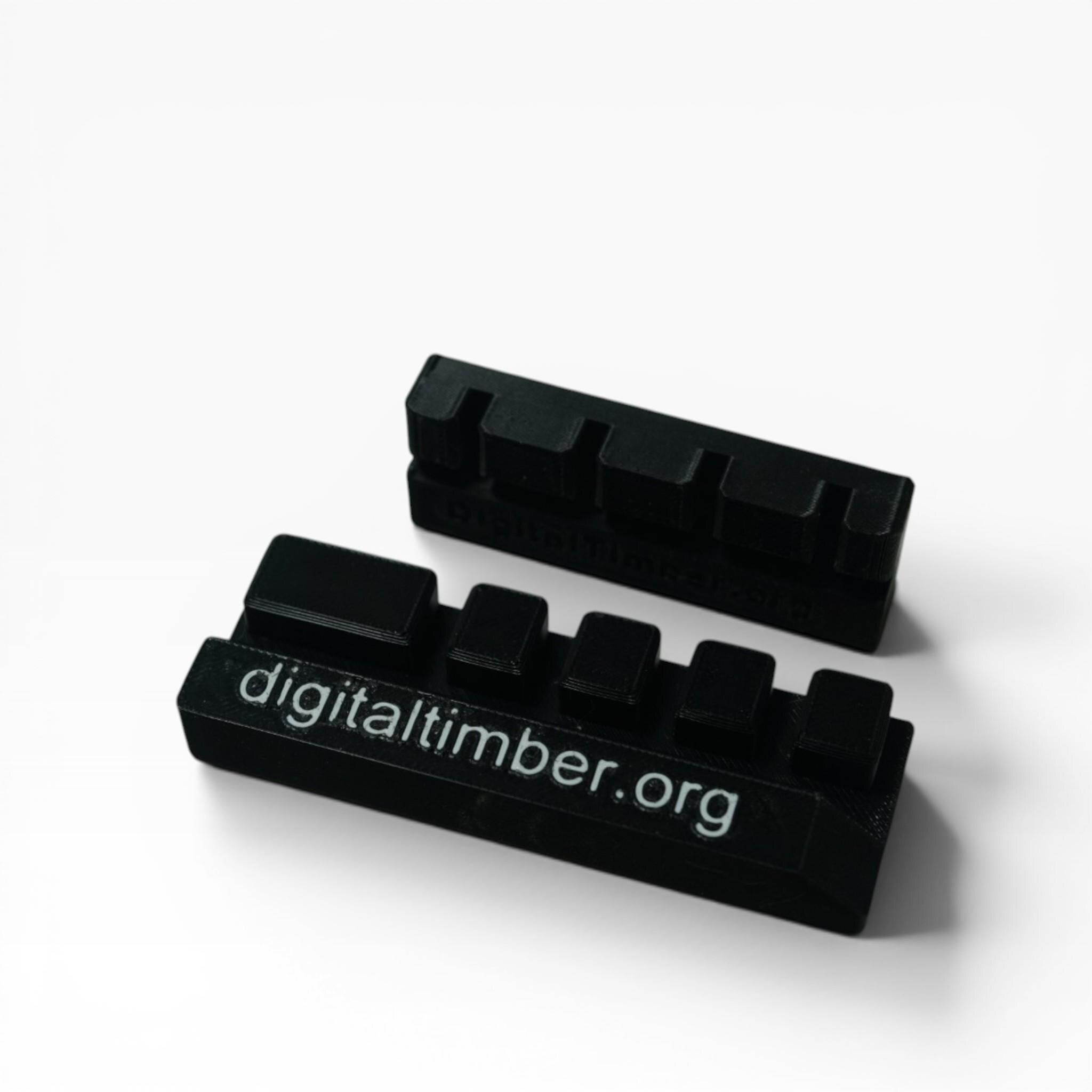 Two black rectangular inserts with four indentations each are angled on a white surface, one with "digitaltimber.org" embossed on its side. __etsy:8332159041
