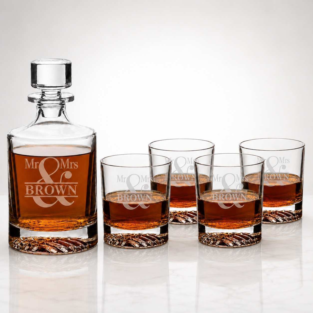 A clear glass decanter and four matching lowball glasses engraved with 'Mr. & Mrs.