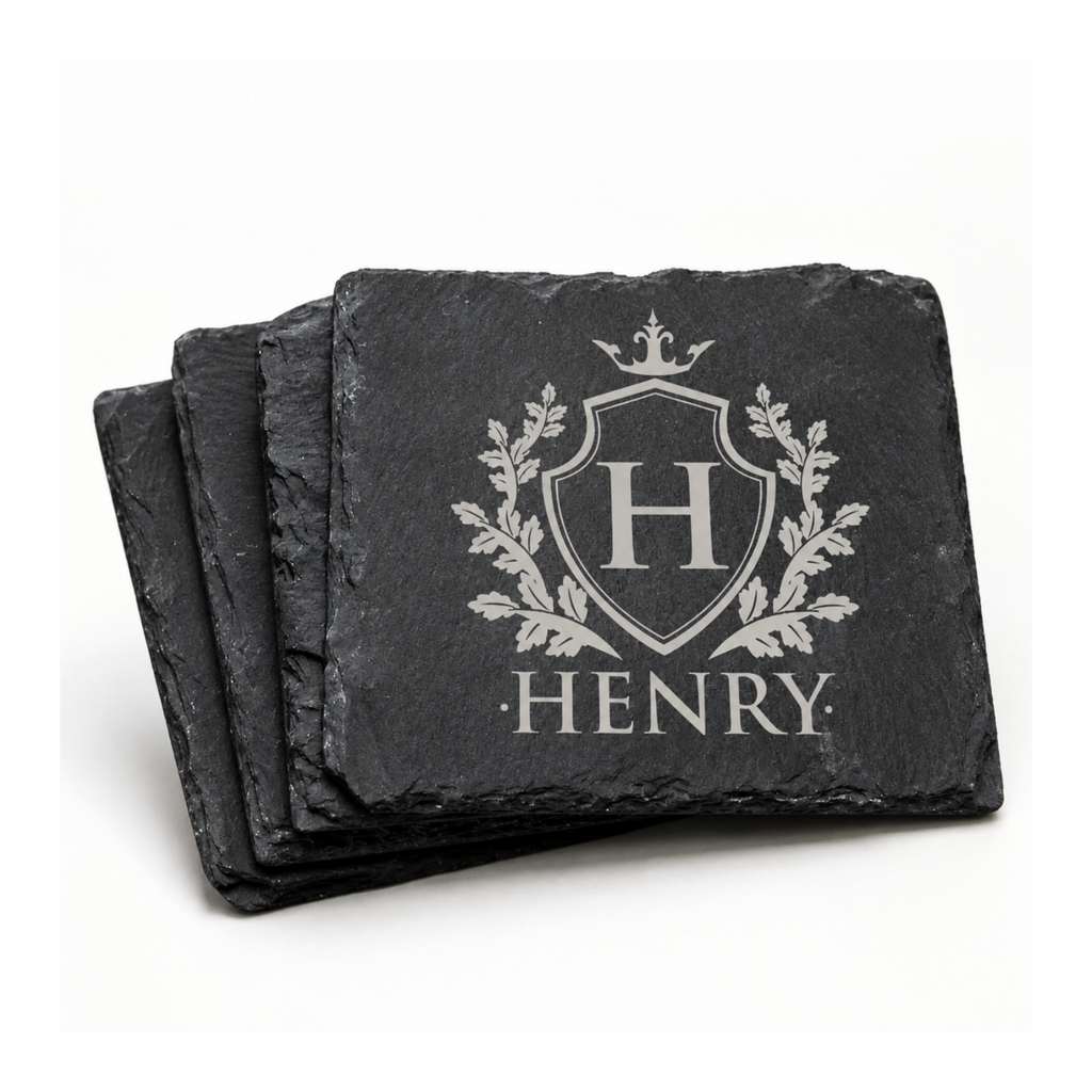 Stack of personalized black slate coasters engraved with a family crest, initial H, and the name Henry.