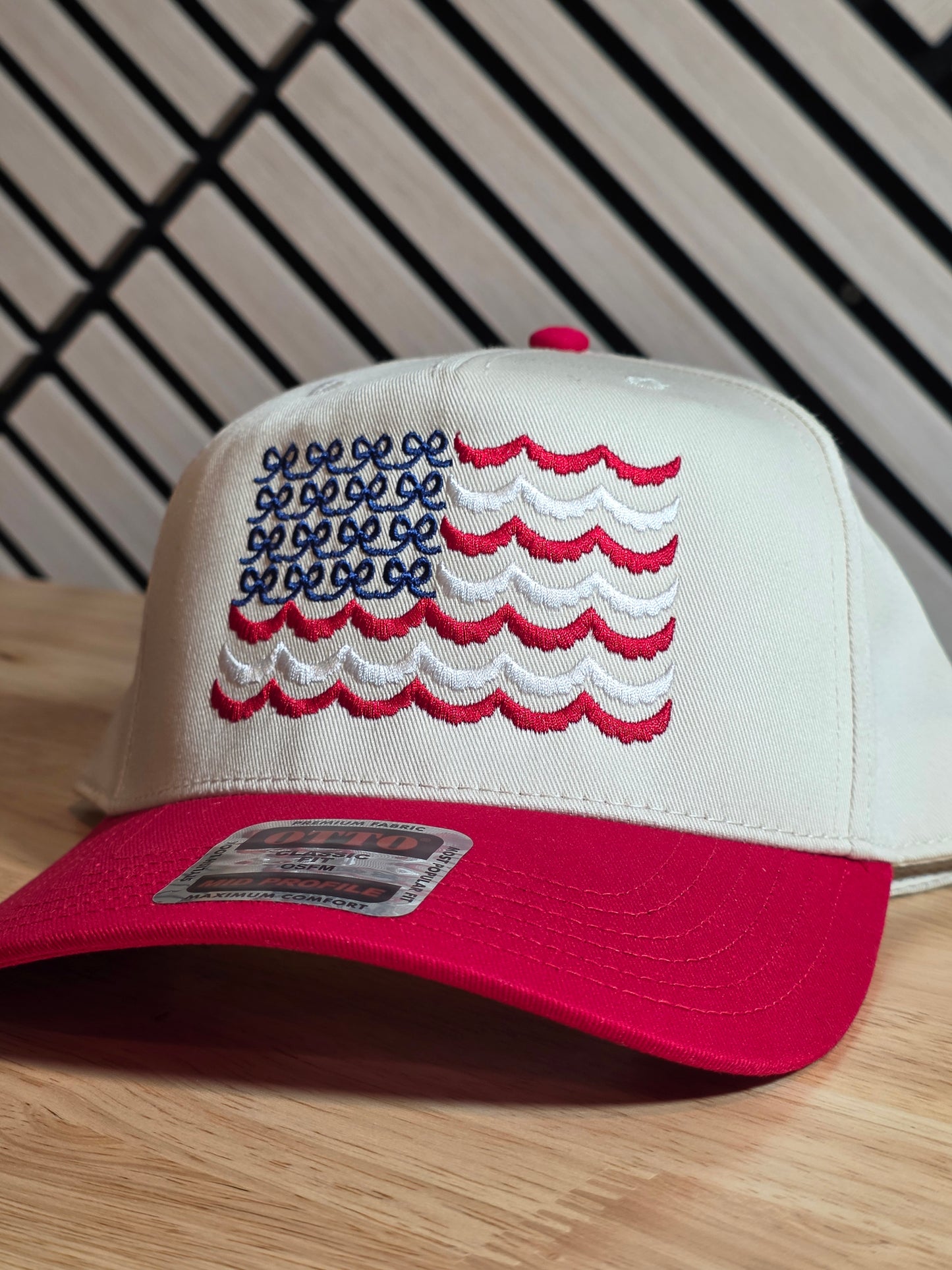 Red and beige cap with embroidered design on a wooden surface