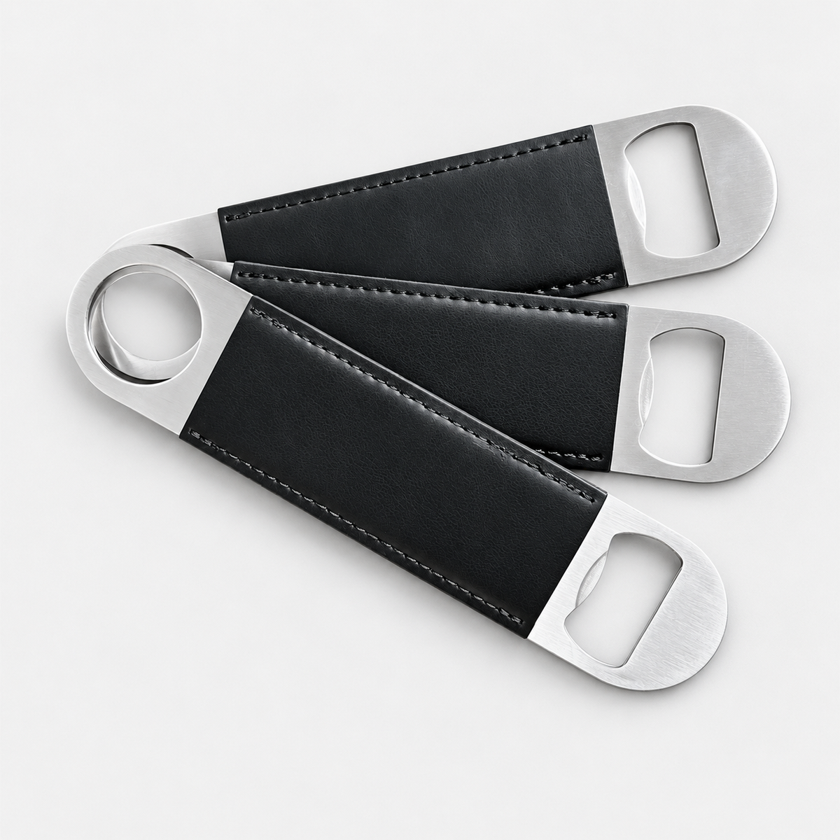 Black leatherette bottle openers before custom UV printing, light gray background